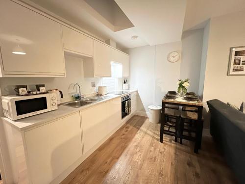 een keuken met witte kasten en een magnetron bij Homes from home by Tulloch Properties in Maidstone