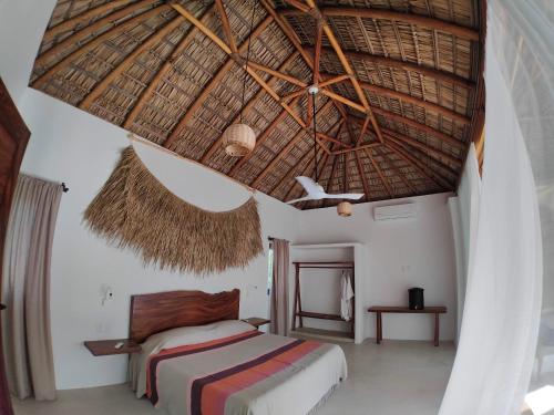 a bedroom with a bed and a straw roof at Casa Kuaa in Brisas de Zicatela