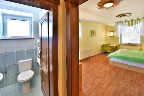 a bathroom with a toilet and a bed in a room at Penzión Víchrica in Veľká Lomnica