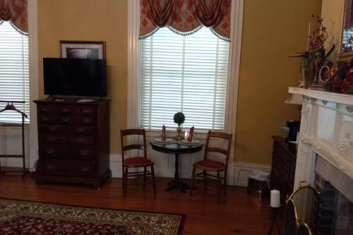 sala de estar con mesa, sillas y TV en Governor's Corner Bed & Breakfast en Russellville