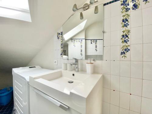 een witte badkamer met een wastafel en een spiegel bij LE NID DES QUAIS - Vue Panoramique au cœur de la ville - Wifi - Entrée autonome in Quimper