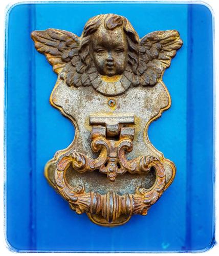 an antique brass angel plaque on a blue door at ALDRAVA POUSADA BOUTIQUE in Tiradentes