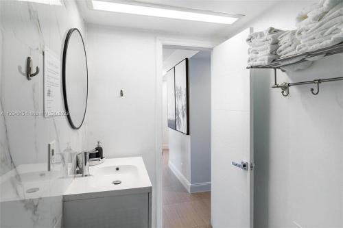Un baño blanco con lavabo y espejo. en 11th - Seven Heaven Miami- Unforgettable Ocean Front- Free Parking, en Miami Beach
