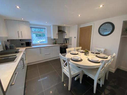 eine Küche mit einem Tisch mit Stühlen und einer Uhr an der Wand in der Unterkunft Modern 4-bed Cottage Llanwrst Town Centre & Parking - Snowdonia! near Betws-y-Coed in Llanrwst