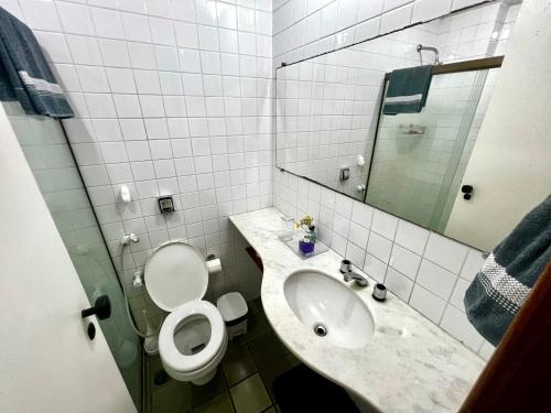 y baño con aseo, lavabo y espejo. en Apto completo na orla da Pituba!, en Salvador