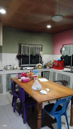 a kitchen with a wooden table and blue chairs at Inap Desa Morni in Kudat