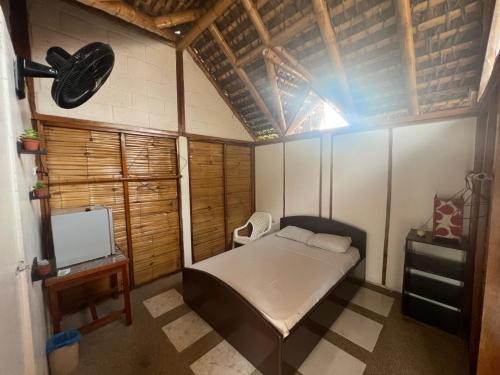 um pequeno quarto com uma cama e uma televisão em Zutalu - Playa Sur em Puerto López