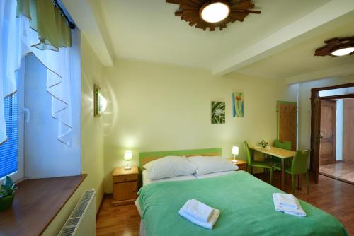 a bedroom with a green bed and a table at Penzión Víchrica in Veľká Lomnica