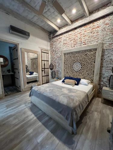 um quarto com uma cama grande numa parede de tijolos em MAHI CASA BOUTIQUE em Cali