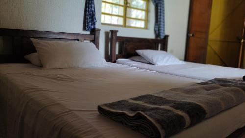 2 Betten mit weißer Bettwäsche und einer Decke darauf in der Unterkunft La posada de Andrea in Pueblo Tapao