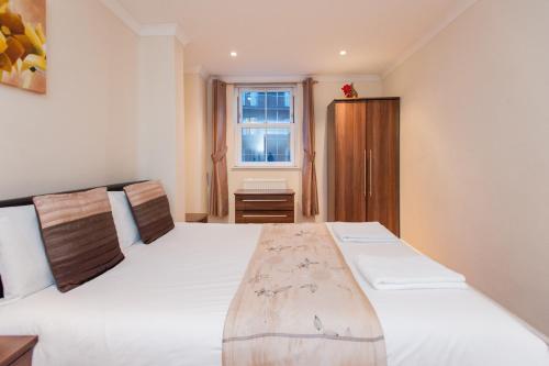 Schlafzimmer mit einem großen weißen Bett und einem Fenster in der Unterkunft London Serviced Apartments in London