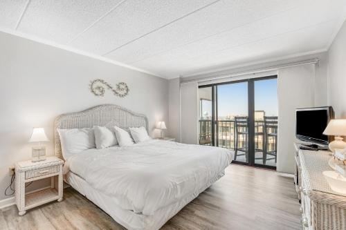 a white bedroom with a large bed and a television at Summer Beach 506 in Ocean City