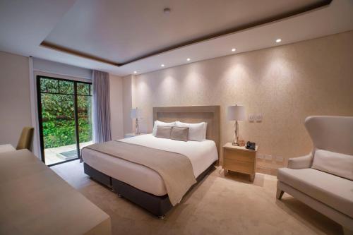 1 dormitorio con 1 cama grande y 1 silla en Alko Hotel Cotona, en Santa Marta