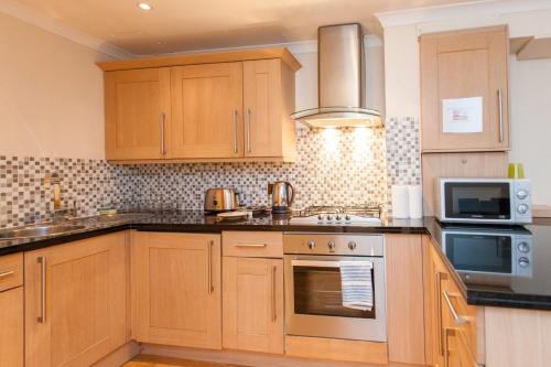 a kitchen with wooden cabinets and a stove top oven at London Serviced Apartments in London