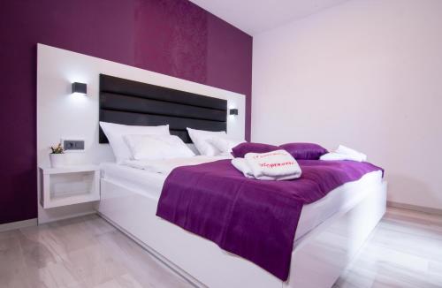 a bedroom with a white bed with a purple blanket at Apartman PAOLA in Vrh