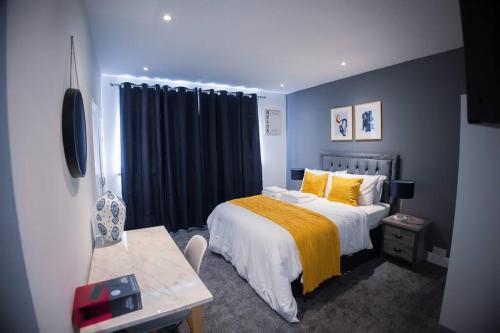 een slaapkamer met een bed met een gele deken en een tafel bij Isinmi Home - Close to MCR City in Manchester