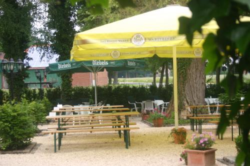 a yellow and green umbrella and tables and chairs at Hotel & Restaurant Venner Moor in Senden