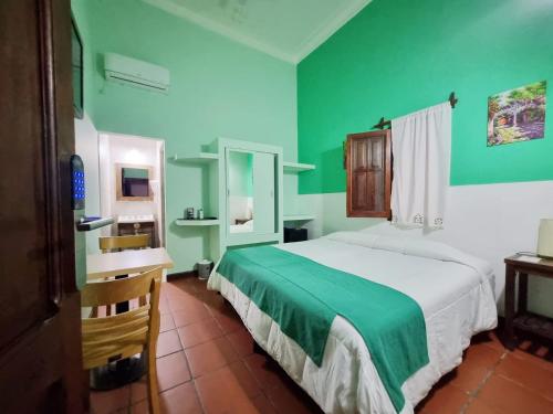 1 dormitorio con cama, escritorio y paredes verdes en Refugio del Inca en Salta