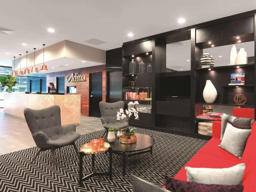 a living room with a red couch and chairs at Adina Apartment Hotel Sydney Airport in Sydney