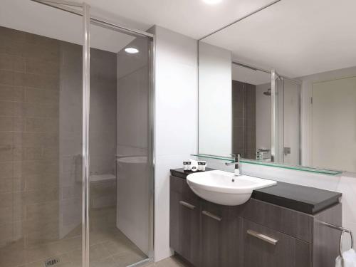 a bathroom with a sink and a glass shower at Adina Apartment Hotel Sydney Airport in Sydney