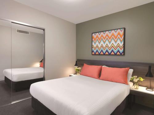 a bedroom with a large bed and a mirror at Adina Apartment Hotel Sydney Airport in Sydney
