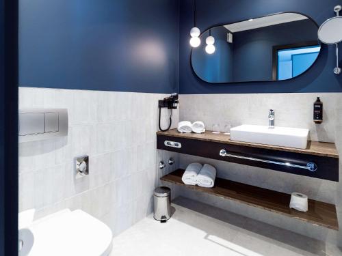 ein Bad mit einem Waschbecken und einem Spiegel in der Unterkunft Mercure Mainz City Center in Mainz
