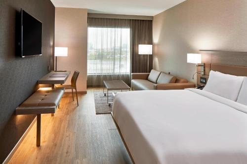 a hotel room with a bed and a couch at AC Hotel by Marriott Cleveland Beachwood in Beachwood