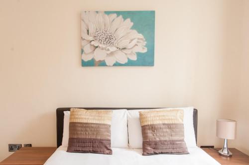 a bedroom with a bed with a flower picture on the wall at London Serviced Apartments in London