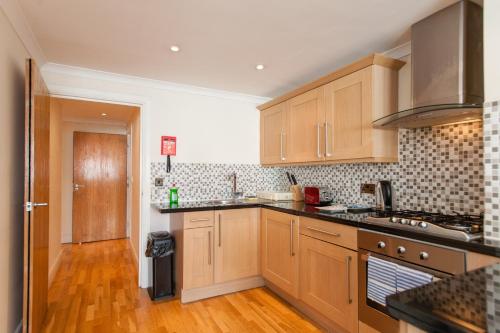 a kitchen with wooden cabinets and wooden floors at London Serviced Apartments in London