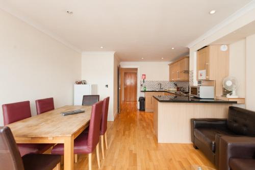a kitchen and living room with a wooden table and chairs at London Serviced Apartments in London