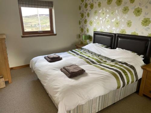 a bedroom with a large bed with two towels on it at The Barn in Lairg