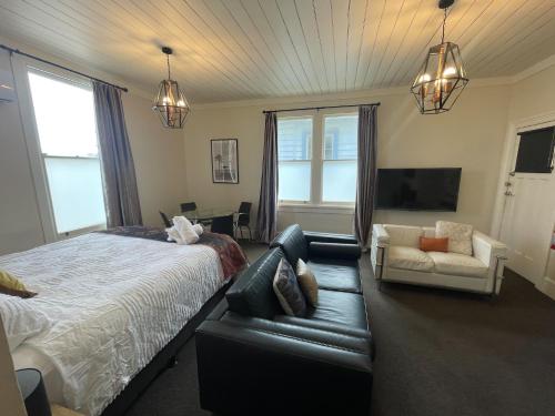 a bedroom with a bed and a couch and a chair at Beach Front Cottage Napier in Napier