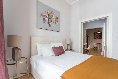una camera da letto con un grande letto bianco con cuscini bianchi di Santa Justa 24 Lisbon Downtown a Lisbona