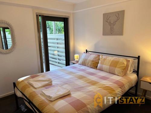 een slaapkamer met een bed met een geruite deken bij Relaxing Oasis in Bruce -1bd 1bth 1 carsp Apt in Belconnen