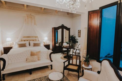 Los Murmullos Casa Boutique por chef Patrick Cros, Campeche في كامبيش: غرفة نوم بسرير ابيض واريكة بيضاء