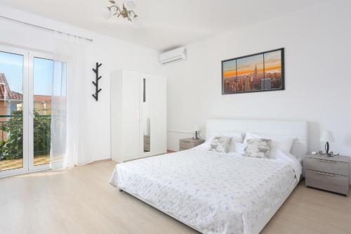 ein weißes Schlafzimmer mit einem weißen Bett und einem Fenster in der Unterkunft Seaside holiday house Poljica, Trogir - 5161 in Marina