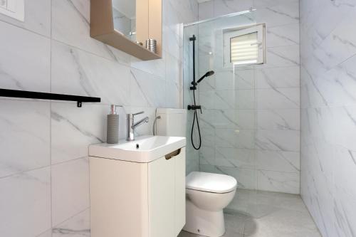 ein weißes Bad mit einem WC und einem Waschbecken in der Unterkunft Seaside holiday house Poljica, Trogir - 5161 in Marina