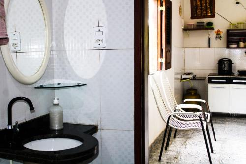 ein Badezimmer mit einem Waschbecken, einem Spiegel und einem Stuhl in der Unterkunft Rancho Boa Vista in Barreirinhas