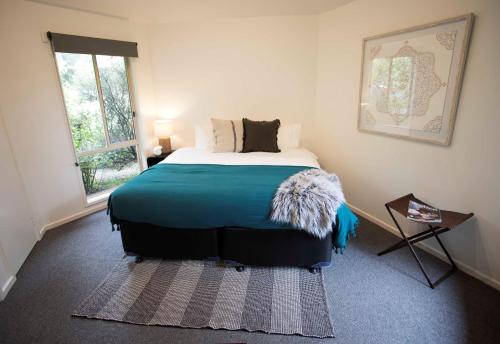 a bedroom with a bed with a blue blanket at MONREPOS in Point Lonsdale