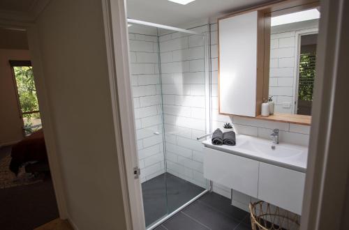 een witte badkamer met een wastafel en een spiegel bij MONREPOS in Point Lonsdale
