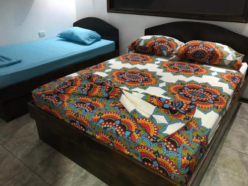 a bed with a colorful quilt and pillows on it at FLOR DE PARAISO BUNGALOWS in Montezuma