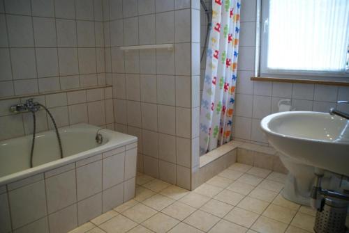 uma casa de banho com uma banheira e um lavatório ao lado de uma banheira em Ferienhaus für 6 Personen ca 96 qm in Großbreitenbach, Thüringen Rennsteig em Großbreitenbach