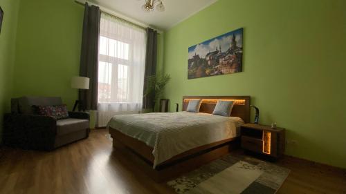 ein grünes Schlafzimmer mit einem Bett und einem Stuhl in der Unterkunft LublinBNB --- Zolnierzy Niepodleglej 7 --- CENTRUM , PLAC LITEWSKI --- SWIEZO PO REMONCIE in Lublin