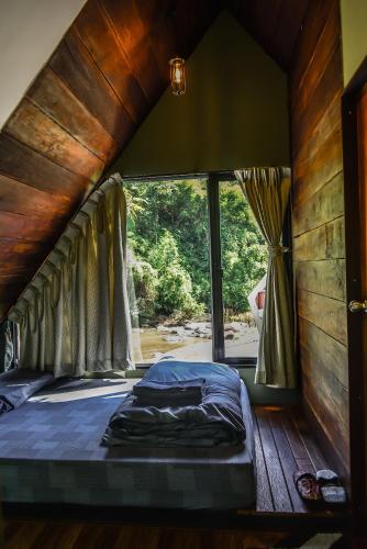a bed in a room with a large window at AomlongHomenon(อมลอง โฮมนอน) in Ban Bong
