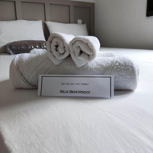 a bed with towels on it with a sign on it at Casa temporada AURORA in São João Batista do Glória