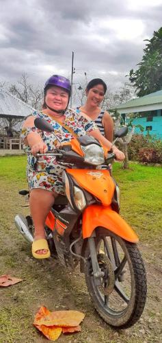 two women are sitting on a motorcycle at House of TamSe Laagans ' Inn in Badian