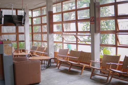 una habitación con un montón de sillas, mesas y ventanas en Augustina Home en Malang