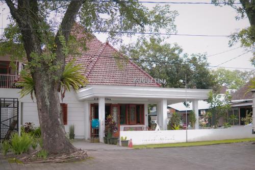 Una casa blanca con un árbol delante. en Augustina Home en Malang