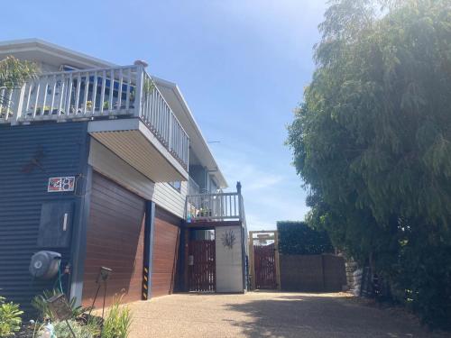 a blue house with a deck and a garage at Beautiful tiny house with outdoor area- Only 5 minute walk to the beach! in Cape Paterson