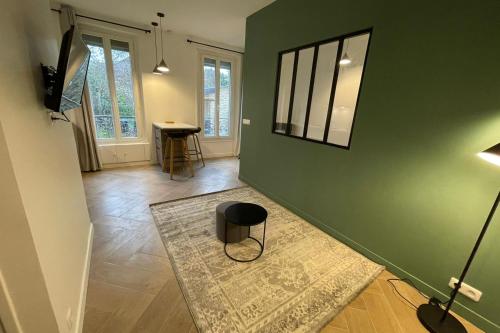una sala de estar con una pared verde y un taburete en Green CityZen Studio Near ParisOrly, en Thiais